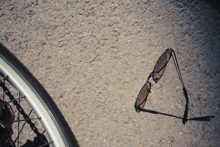 Sunglasses on the asphalt next to bicycle wheels.の写真素材