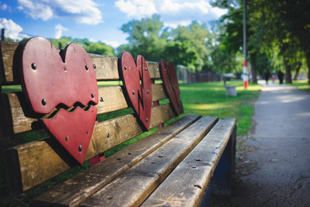 A red wooden heart as a decoration on a bench on a city promenade, a football field in the...