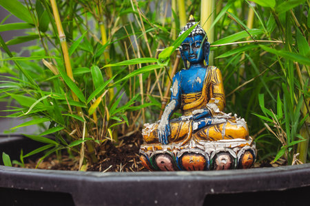 Old chipped Buddha souvenir as decoration in flowers.の写真素材