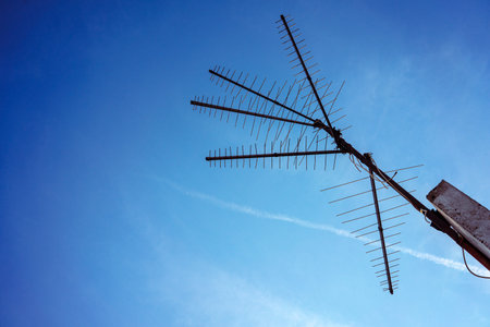 Old radio and television house antennas on a concrete wall, blue sky in the background.の写真素材