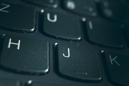 Part of a black laptop keyboard with focus on the J key.の写真素材
