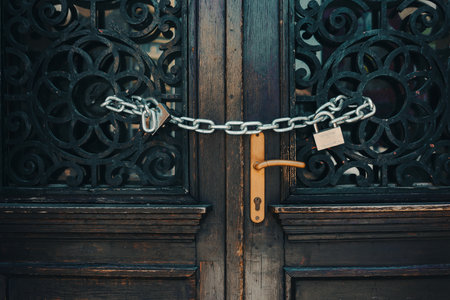 A metal chain with a padlock over an old wooden door with decorative frames.の写真素材