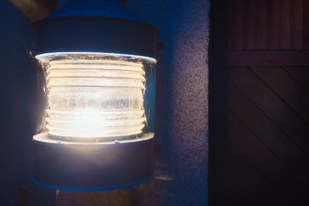 Large wall garden lamp, cobweb with spiders around the perimeter, in the background of the facade of the wall.の写真素材