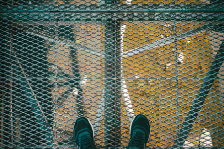 Standing on a metal grate on a bridge over a river.の写真素材