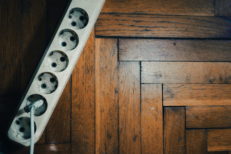 Power distributor for plugs, top view, old parquet in the background.