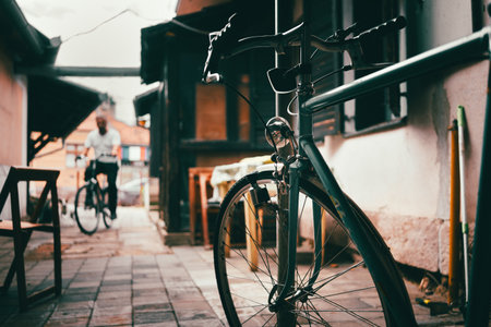 Parked bike in the yard of the household, in the distance you can see a man on another bike.の写真素材
