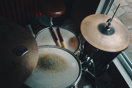 Old jazz drum kit with reeds on the drum next to the window.