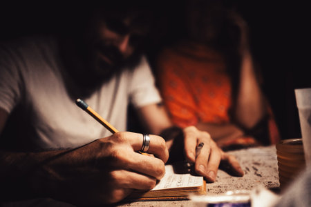 Hands of young man with ring in focus, taking notes or jotting down ideas.
