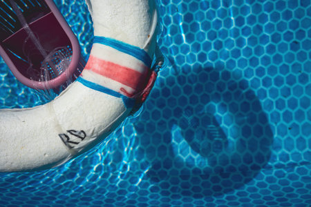 Lifebuoy in pool, top view, abstract composition.