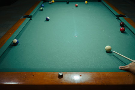 A player prepares to play his next move on a large pool table in a night pub.