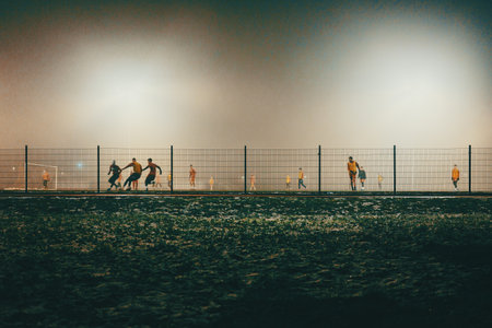 Night scene of soccer fields with players in autumn, foggy atmosphere.の写真素材