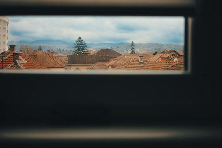View through the window of the city rooftops and hills in the distanceの写真素材