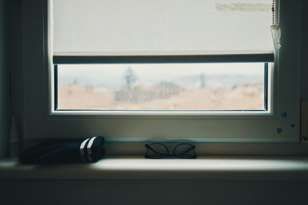 Glasses and winter gloves by the window during the day.の写真素材