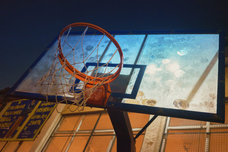 Basketball hoop and transparent backboard, bottom close up view, night scene.