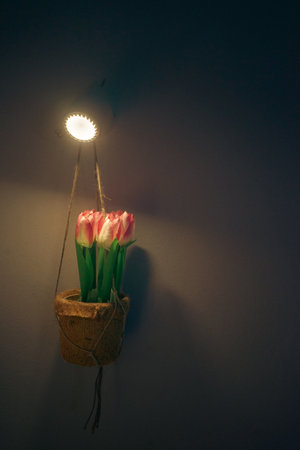 Artificial flowers in a wicker vase hanging on a wall lamp.の写真素材