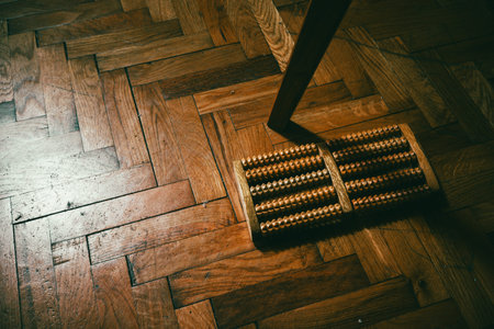Wooden foot massager on parquet, top view, abstract composition.