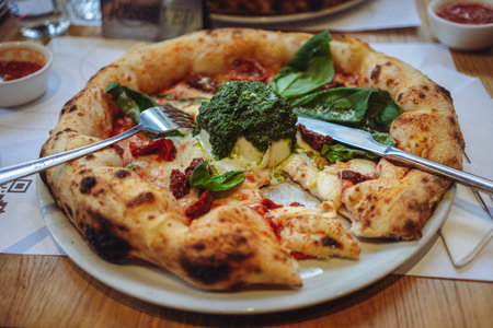 Rich Italian pizza with plenty of ingredients on a restaurant table, close-up details.