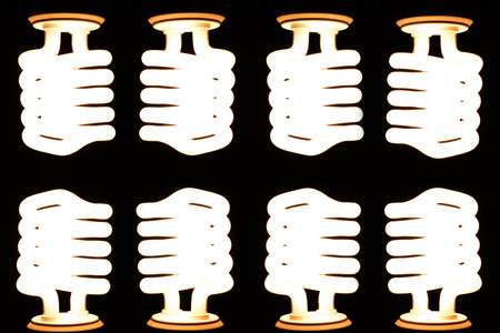 Energy saving light bulb glowing on dark background.の写真素材