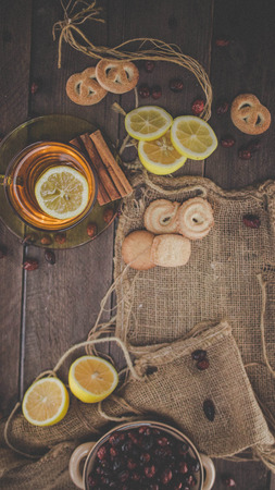 Dried fruits hip tea with lemon and cookies on wooden tableの写真素材