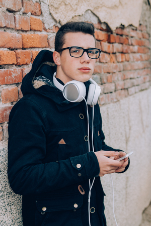 Smiling young man listening to music on smart phone with headphonesの写真素材