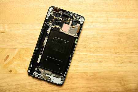 Parts of disassembled Smartphone on wooden table, selective focus, overhead viewの写真素材