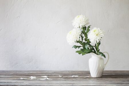 white chrysanthemum in jug on background old wallの写真素材