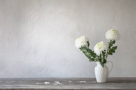 white chrysanthemum in jug on background old wallの写真素材