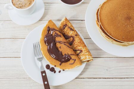 pancakes with chocolate and coffee on white wooden backgroundの写真素材