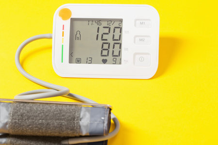 modern tonometer on yellow background, pressure 120 to 80 on  monitor