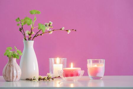 spring cherry flowers and candles on pink backgroundの写真素材