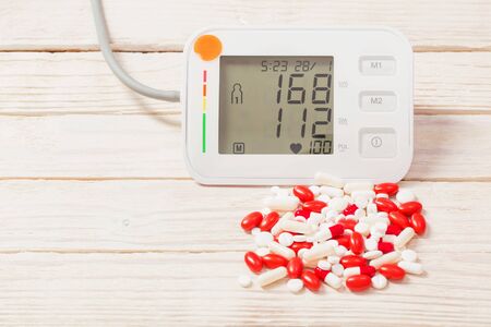 modern tonometer with pills on wooden backgroundの写真素材