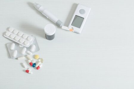 glucometer and pills on  white wooden tableの写真素材