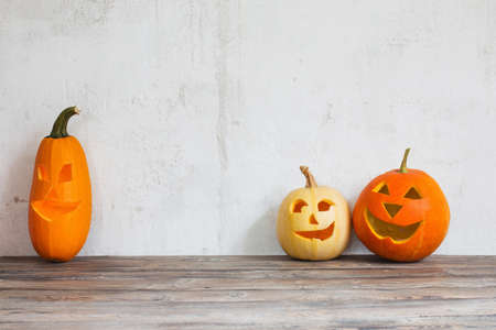 Halloween pumpkins on wooden table on background old white wallの写真素材