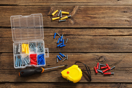 construction tape, screwdriver and dowels on dark wooden background