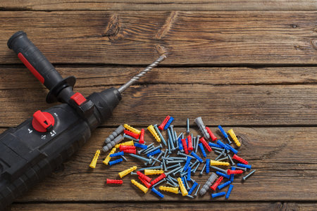 electric screwdriver and dowels on dark wooden background