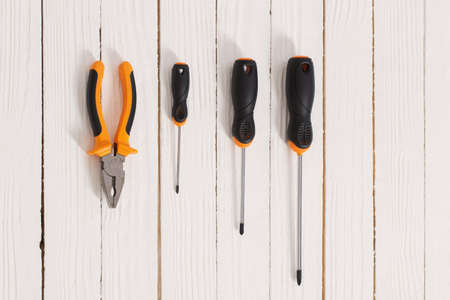 set of screwdrivers and pliers on white wooden backgroundの写真素材