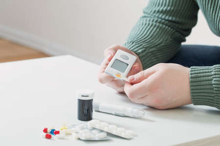 person measures blood sugar with glucometerの写真素材