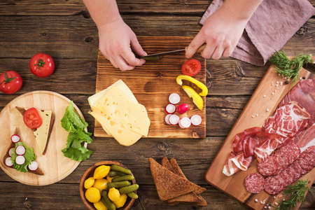 making sandwiches with meat and sausage on wooden tableの写真素材