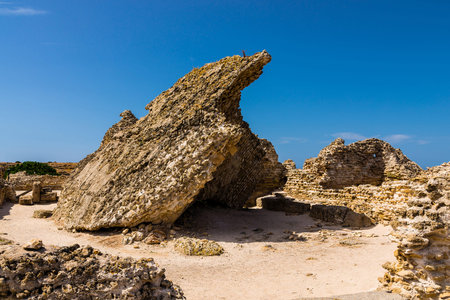 Ancient stone ruins of Nora in Sardegna, Italy. Brick, stone and sand under blue sky. Archeological place Nora in Sardiniaの写真素材
