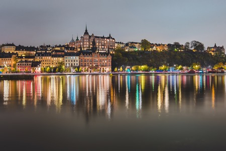 Stockholm city lights and night view of Sodermalm district buildings reflected in the water. Evening Stockholm cityscape with illumination, Riddarfjarden marina and Soder Malarstrand embankment.の写真素材