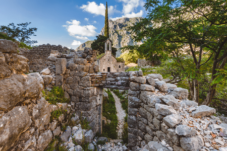 Ancient Serbian church, city ruins and mountain valley landscape near Kotor castle in Montenegro. Old mountain church and monastery in Kotor region near path to Lovchen mountain. Saint Ivan chapel.の写真素材
