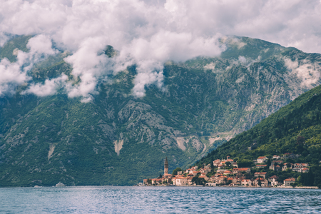 Famous ancient Perast coast town on Kotor bay by cloudy day in Montenegro. View to Perast Old Town roofs and cloudy mountains from water of Boka Kotorska. Postcard montenegrin landscape.の写真素材