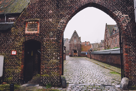 New Saint Elisabeth beguinage entrance in Sint-Amandsberg district, Ghent, Belgium. Known as Groot Begijnhof Sint-Amandsberg. Brick belgium houses, cobbled street and archway by rainy day in Gent.のeditorial素材