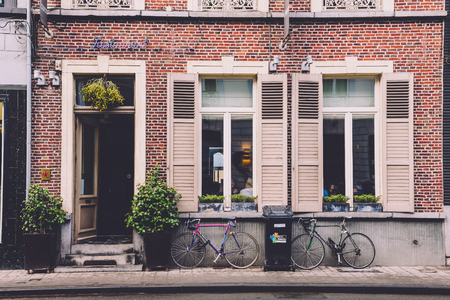 January, 3th, 2017 - Ghent, East Flanders, Belgium. Empty street, restaurant entrance door, shuttered windows and parked bike pair. Modern bicycles standing near brick wall in belgian city Gent.のeditorial素材