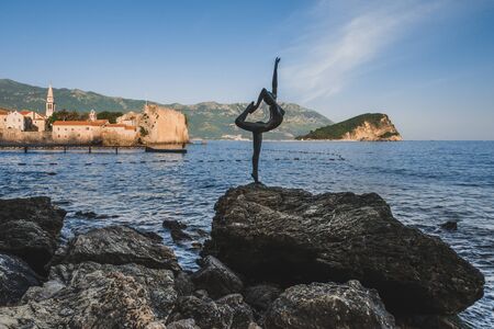 May, 30th, 2016 - Budva, Montenegro. Dancing Girl statue silhouette on Budva Old Town Citadele and Adriatic sea background. Medieval walls and red tiled roofs by golden hour.のeditorial素材