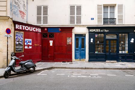 Paris, France - August 11, 2017. Typical street scene in Paris with restaurant, shop and scooter. Narrow French lane with vintage colorful exterior and traditional white blinds.のeditorial素材