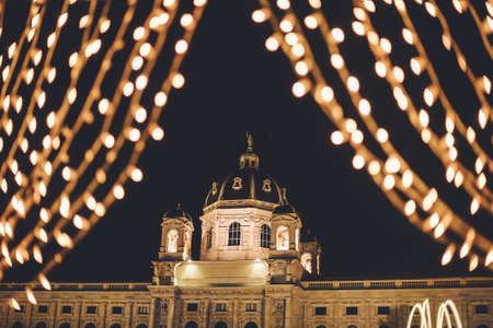 Vienna, Austria - December 25, 2017. Natural History Museum, or Kunsthistorisches framed with illuminated garlands in Christmas. Vienna winter festive fair lights at Maria Theresien Platz by night.のeditorial素材