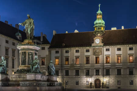 Vienna, Austria - December 24, 2017. Hofburg royal palace courtyard with statue of emperor Francis II in evening. Hapsburg empires old baroque building with illumination at dusk with no people.のeditorial素材