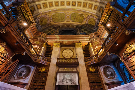 Vienna, Austria - December 24, 2017. Interior of Austrian National Library with craved wood bookshelves and molding. Hapsburg empires old baroque library hall with rare ancient folios and old maps.のeditorial素材