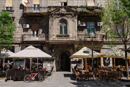 Belgrade, Serbia - April 19, 2018. Street cafe terraces with relaxing people in Belgrade center. Spring city scene with restaurants in old architecture building.のeditorial素材